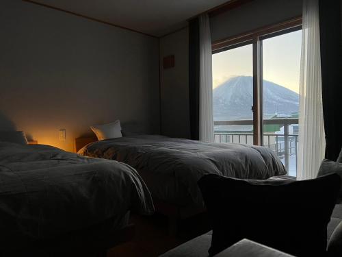 twee bedden in een kamer met uitzicht op een berg bij SLOPE in Kutchan