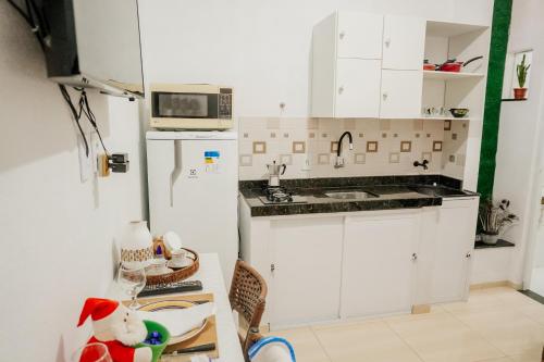 una pequeña cocina con armarios blancos y microondas en Studio à 400m mar,cozinha completa, wi-fi 95mbs ideal para casais, en Prea