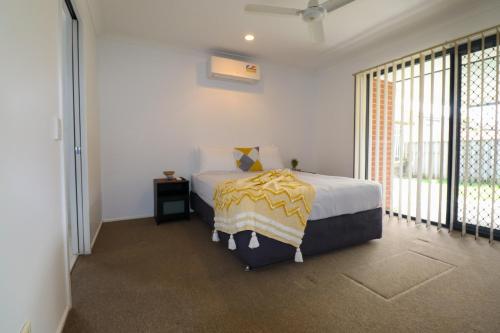 a bedroom with a bed and a large window at BLK Stays Guest House Deluxe Units Bellmere 