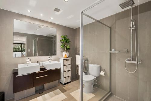 een badkamer met 2 wastafels, een douche en een toilet bij Nautical Beach Vibe - Downtown Mount/Beach in Mount Maunganui