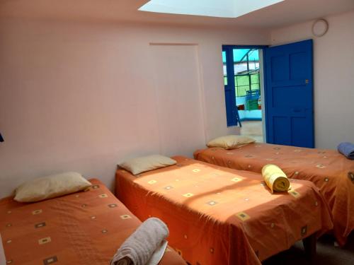 een kamer met drie bedden en een blauwe deur bij Posada Azul Cusco in Cuzco