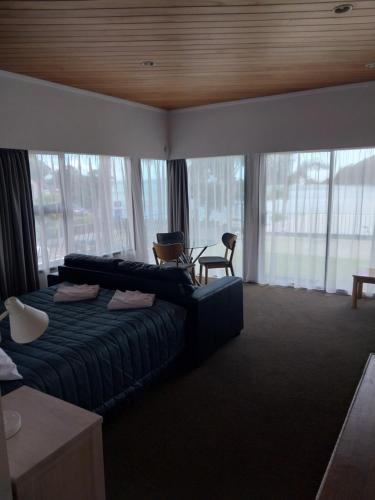a hotel room with a bed and a chair and windows at Bayview Motel in Paihia