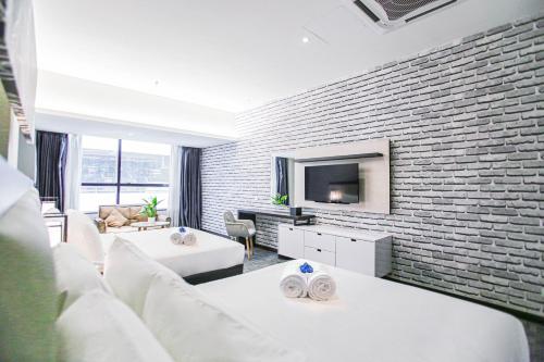 a living room with white furniture and a brick wall at Fives Hotel DNP in Johor Bahru