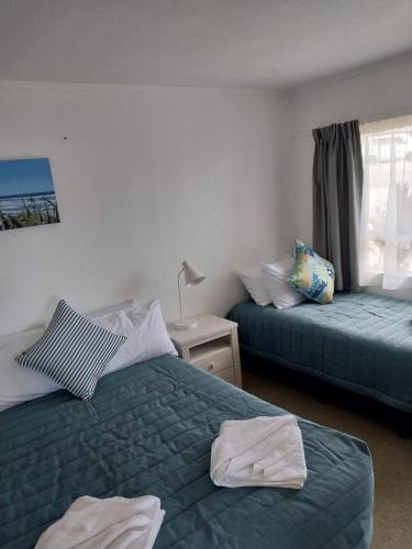 a bedroom with two beds with towels on them at Bayview Motel in Paihia