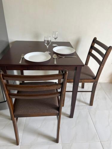 a wooden table and chairs with wine glasses on it at Reinhardshausen Suites and Residences - Cozy Air-conditioned Units in Tuguegarao City