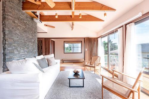 ein Wohnzimmer mit einem weißen Sofa und einer Ziegelwand in der Unterkunft Villa Sunshine in Ito