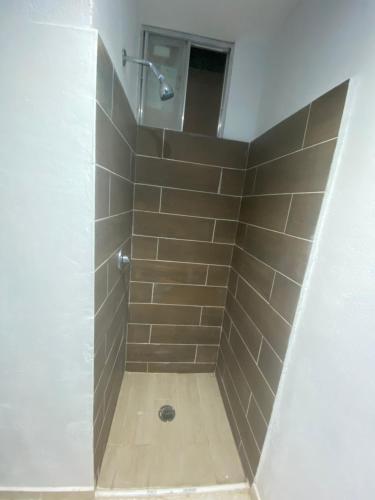 een badkamer met een douche en een tegelwand bij Cuarto Ajalpan 