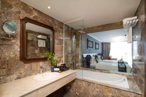 a bathroom with a tub and a sink and a large mirror at Pistachio Hotel Sapa in Sa Pa