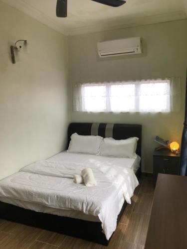 Bendang Homes - Sekinchan Homestay في Kampong Sungai Leman: غرفة نوم بسرير ابيض عليها منشفة بيضاء