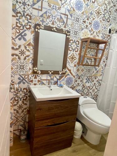 a bathroom with a sink and a toilet and a mirror at Qeru House in Zorritos