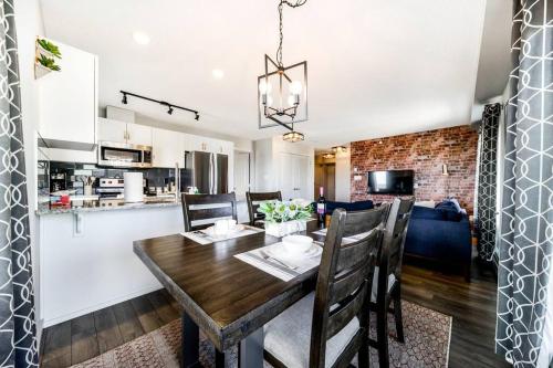 a kitchen and dining room with a wooden table and chairs at Bright Luxe Condo, AC, Top Floor, King Bed, Balcony! in Edmonton