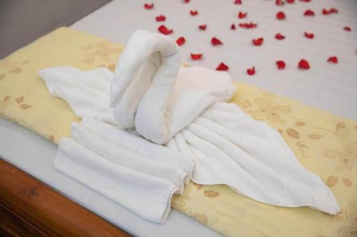 een groep witte handdoeken op een bed met aardbeien bij BOBE Homestay in Hội An