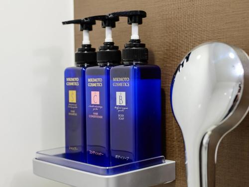 two blue bottles are sitting next to a spoon at Hotel Tsu Center Palace in Tsu