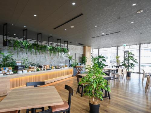 a restaurant with tables and chairs and plants at Hotel Tsu Center Palace in Tsu