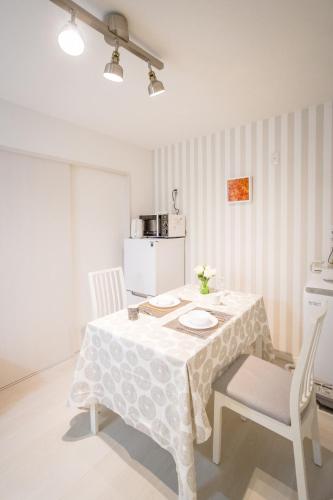 a white table with two chairs and a white refrigerator at HANASTAY花渓居 · 楓（KAEDE) in Osaka