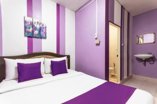 a purple and white bedroom with a bed and a sink at Riverside Guesthouse in Khao Lak