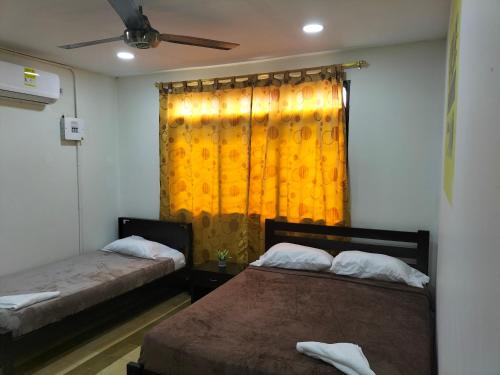 um quarto com 2 camas e uma cortina amarela em Alojamiento Mamá Juana em Ríohacha