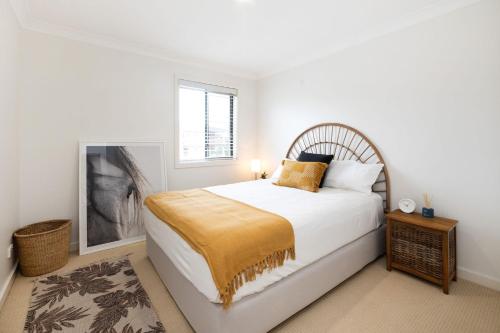 a white bedroom with a bed and a window at El Portil in Ulladulla