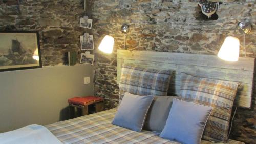 sypialnia z łóżkiem z 2 poduszkami i kamienną ścianą w obiekcie Le Cottage w mieście Saint-Sébastien-sur-Loire