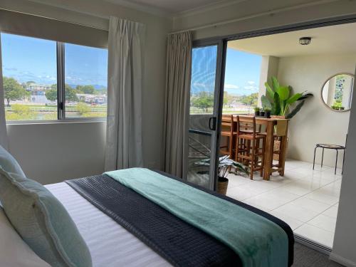 a bedroom with a bed and a balcony with a table at City Stadium Apartment on the Riverfront 38 in Townsville