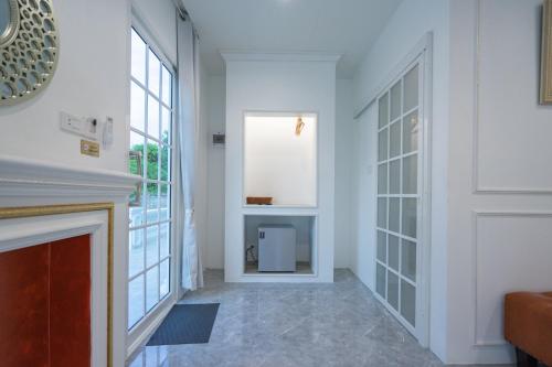 ein Wohnzimmer mit weißen Wänden und einem Kamin in der Unterkunft Je t'aime cafe & villa in Sing Buri