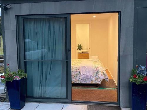 eine Glastür, die zu einem Schlafzimmer mit einem Bett führt in der Unterkunft Great Ocean Road Wellness and Nature Stay in Apollo Bay