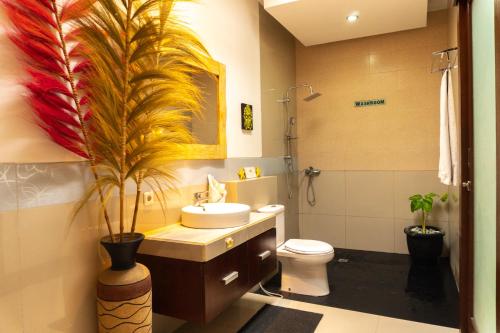 a bathroom with a sink and a toilet with a plant at Wyanna Villa LEGIAN in Legian