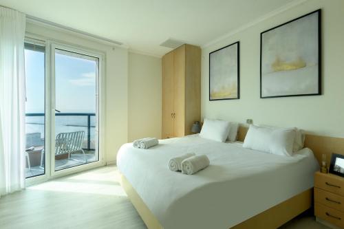 um quarto com uma grande cama branca e uma grande janela em Luxury 2BR Apt w Balcony, Pool Access & Beach View by Sea N' Rent em Tel Aviv