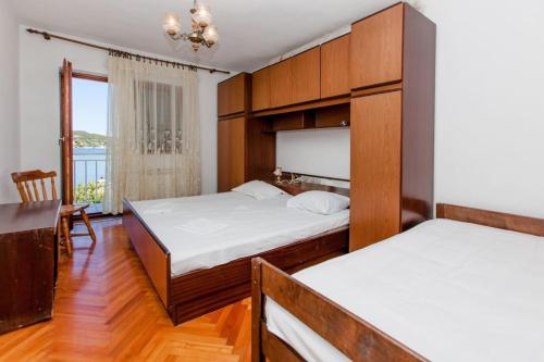 een slaapkamer met 2 bedden, een tafel en een raam bij Apartments Jere - 30 m from beach in Vinišće