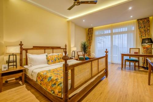 a bedroom with a bed and a desk and a window at Summit Barsana Resort & Spa in Kalimpong