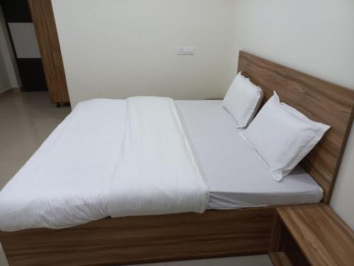 a bed with white sheets and pillows in a room at HOTEL TIRATH in Rishīkesh