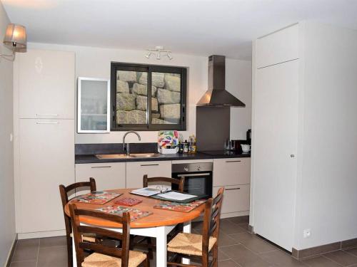 - une cuisine avec une table, des chaises et un évier dans l'établissement Maison neuve à Trégastel avec WIFI, terrasse en bois et classée 3 étoiles, près des plages - FR-1-368-72, à Trégastel