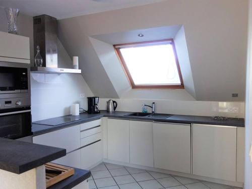 une cuisine avec des armoires blanches et une fenêtre dans l'établissement Villa avec Jardin Calme, Proche Plages et Commerces à Perros-Guirec - FR-1-368-267, à Perros-Guirec