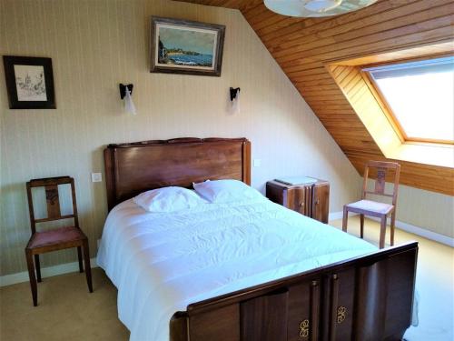 une chambre avec un grand lit et deux chaises dans l'établissement Villa avec Jardin Calme, Proche Plages et Commerces à Perros-Guirec - FR-1-368-267, à Perros-Guirec