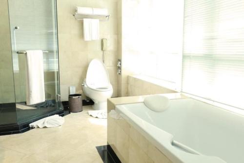 a bathroom with a toilet and a sink and a tub at Miracle Grand Convention Hotel in Bangkok