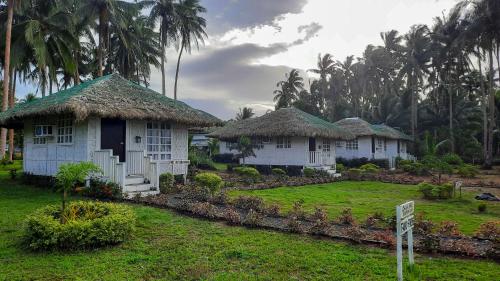 dos casas blancas con techo de paja en un patio en Kehalani Beach Resort by Cocotel en Quezon