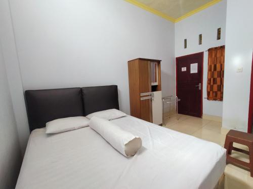 ein Schlafzimmer mit einem großen weißen Bett mit zwei Kissen in der Unterkunft Inawa Homestay Syariah in Rampal