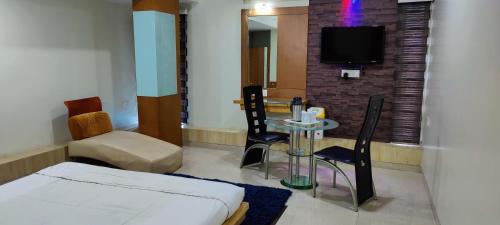 a room with a bed and a table and a tv at Hotel Easy Retreat in Vapi