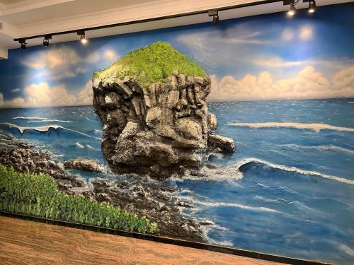 Un dipinto di una roccia nell'acqua su un muro di Shange Beach Club Homeatay a Città Vecchia di Hengchun