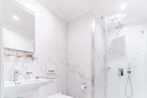 a white bathroom with a shower and a sink at VIZUALIZA Residence Hotel in Plovdiv