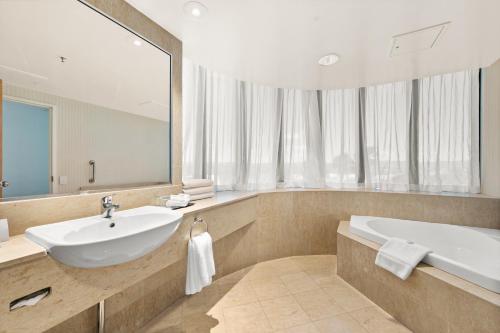 La salle de bains est pourvue d'un lavabo, d'une baignoire et d'un miroir. dans l'établissement Crowne Plaza Surfers Paradise, an IHG Hotel, à Gold Coast