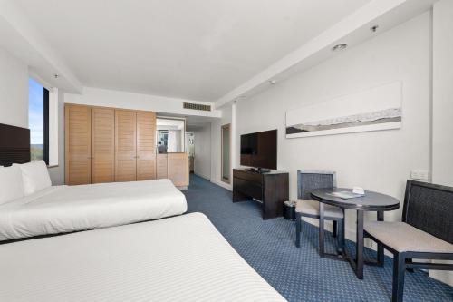 ゴールドコーストにあるクラウンプラザ サーファーズ パラダイスのベッド2台とテーブルが備わるホテルルームです。