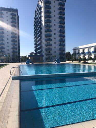 a large swimming pool with buildings in the background at Amazing seaview studio with pool-steps away beach in Áyios Yeórgios