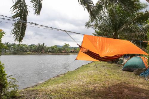 an orange umbrella attached to a tent next to a lake at Sahom Valley Resort - Agro & Eco Park in Kampar