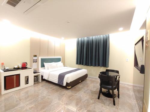 1 dormitorio con cama, escritorio y silla en Jeju Irrua Hotel en Jeju