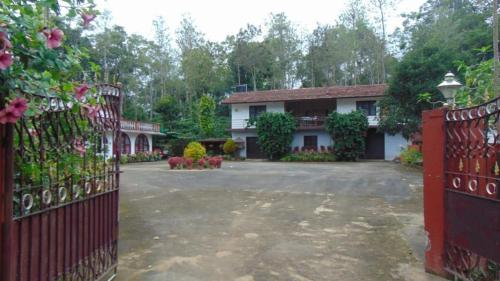 dom z czerwoną bramą i podjazdem w obiekcie Shree Raksha Homestay w mieście Gonikoppal