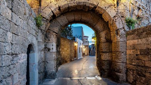 an alley with an archway in a stone wall at Kókkini Porta Rossa in Rhodes Town