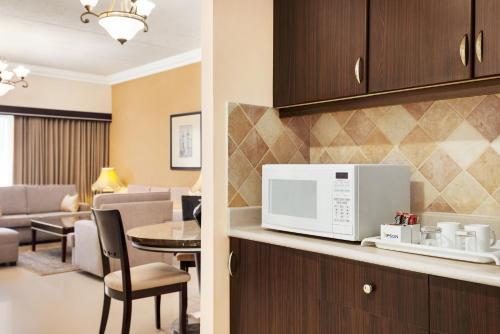a kitchen with a microwave and a living room at Eastyard Dammam Hotel - Formerly Ramada by Wyndham Dammam in Dammam