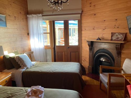 a bedroom with two beds and a fireplace and a chandelier at Winterbrook House in Ulverstone