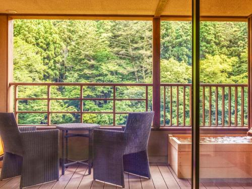 eine Veranda mit Stühlen und einem Tisch auf dem Balkon in der Unterkunft Shionoyu Onsen Rengetsu in Nasushiobara